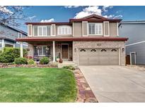 Charming two-story home features a brick facade, covered porch, manicured lawn, and attached two-car garage at 4907 Fenwood Dr, Highlands Ranch, CO 80130