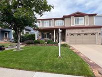 Charming two-story home with a well-manicured lawn, brick accents, and a welcoming front porch with flower accents at 4907 Fenwood Dr, Highlands Ranch, CO 80130