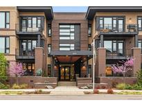 Inviting three-story condo building featuring brick facade, black accents, street-level landscaping and covered entry at 6619 E Lowry Blvd # 101, Denver, CO 80230