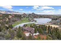 Stunning aerial view of a lakeside home next to golf course with beautiful mountain views and an inviting exterior at 7267 Comanche Ct, Larkspur, CO 80118