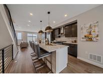 Open kitchen with quartz countertop island, pendant lighting, and stainless steel appliances at 2430 Ames St, Edgewater, CO 80214