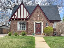 Charming brick Tudor-style home featuring a unique roofline, well-kept lawn, and inviting front walkway at 3055 N Albion St, Denver, CO 80207