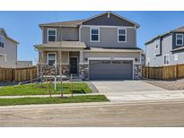 Two-story home featuring a two-car garage, stone accents, neutral siding, and a well-manicured lawn at 17467 E 89Th Way, Commerce City, CO 80022