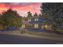 Charming two-story home with brick and beige siding, a covered porch, and mature trees at 8102 S Zephyr St, Littleton, CO 80128