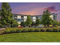 Modern condo building with lush landscaping and a colorful dusk sky at 2958 Syracuse St # 403, Denver, CO 80238