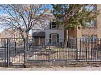 Charming home with a black iron fence, mature trees, and a two-door entrance beneath a striped awning at 1554 N Pennsylvania St, Denver, CO 80203