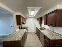 Well-lit kitchen with granite countertops, tile floors and stainless steel appliances at 2929 W Floyd Ave # 217, Denver, CO 80236