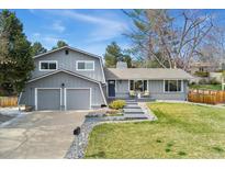 Charming two-story home with a well-maintained front yard, garage, and a cozy seating area on the front porch at 2477 S Dover Way, Lakewood, CO 80227