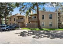 Two-story condo buildings featuring balconies, wooden fences, and assigned parking with mature trees at 8050 Niwot Rd # 40, Niwot, CO 80503