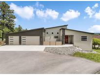 Modern home exterior with a stylish facade, three-car garage, and a vibrant red front door at 3630 Mesa Verde Rd, Monument, CO 80132
