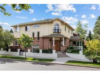 Inviting two-story home showcasing a beige stucco facade complemented by brick accents, a balcony, and manicured landscaping at 2400 S Clayton St, Denver, CO 80210