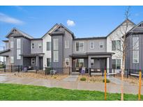 Modern townhouse exteriors with gray siding, large windows, and well-maintained landscaping under a blue sky at 430 Millwall Cir, Castle Pines, CO 80108
