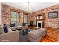 Charming living room with exposed brick walls, hardwood floors, a fireplace, and large windows at 1210 E Colfax Ave # 302, Denver, CO 80218