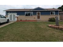 Charming single-story home featuring a blue painted exterior, brick accents, and a well-manicured front yard at 290 W 1St Ave, Broomfield, CO 80020