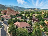 Stunning aerial view of a neighborhood nestled amongst picturesque rock formations and lush greenery with mountain views at 10751 Fairway Vistas Ct, Littleton, CO 80125
