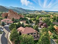 Beautiful aerial view of homes nestled amongst trees with stunning red rock formations and mountain views at 10751 Fairway Vistas Ct, Littleton, CO 80125