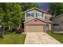 Charming two-story home with a brick facade and well-maintained lawn and mature trees at 1440 E 128Th Ct, Thornton, CO 80241