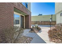 Brick townhome with a modern entryway featuring a glass door, concrete walkway, and decorative rock landscaping at 2114 N Clay St, Denver, CO 80211