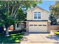 Charming two-story home with a large front yard and attached two-car garage on a sunny day at 10064 Westside Cir, Littleton, CO 80125