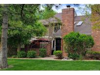 Charming townhome featuring a brick chimney, manicured lawn, and covered front porch at 11710 Elk Head Range Rd, Littleton, CO 80127