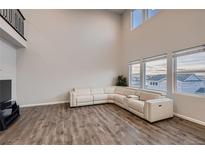 Bright living room with a large sectional sofa, wood floors, and soaring ceilings with many windows allowing ample natural light at 17203 Birds Foot Ave, Parker, CO 80134