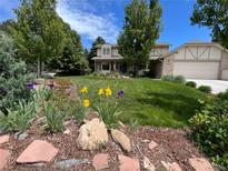 Well-maintained two-story home featuring a beautiful lawn and manicured garden beds at 1324 Shadow Mountain Dr, Highlands Ranch, CO 80126