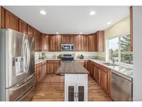 Well-lit kitchen features stainless steel appliances, wood cabinets, granite counters, island and hardwood floors at 16523 High Desert Pl, Parker, CO 80134