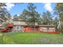 Charming two-story home with a spacious deck, beautiful stonework, and set amongst mature trees at 28735 Little Big Horn Dr, Evergreen, CO 80439