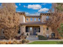 Tan two-story townhome with a covered entryway, landscaping, and a grassy front yard at 6725 S Versailles Way # 101, Aurora, CO 80016