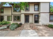 Charming townhouse with neutral siding, a dark front door, and a beautiful rock and garden landscape at 3571 S Kittredge St # C, Aurora, CO 80013