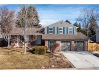 Charming two-story home boasts a well-maintained yard, brick facade, and a spacious two-car garage at 7220 S Lewis St, Littleton, CO 80127