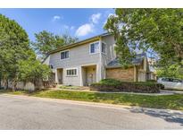 Charming gray two-story townhome showcasing brick accents, mature landscaping, and assigned parking in a desirable community at 2238 S Nome Ct, Aurora, CO 80014
