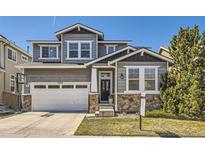 Charming gray two-story home with stone accents, a basketball hoop, and a well-manicured lawn at 3024 Woodbriar Dr, Highlands Ranch, CO 80126