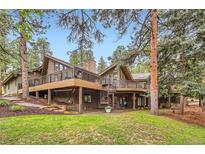 Stunning home featuring a multilevel deck, spiral staircase, manicured lawn, and mature trees at 4856 Cheyenne Dr, Larkspur, CO 80118
