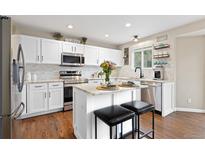 Bright kitchen features white cabinetry, granite countertops, stainless steel appliances, and a breakfast bar at 2763 Dharma Ave, Broomfield, CO 80020