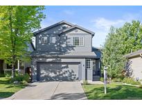 Charming two-story home with a gray exterior, well-manicured lawn, and attached two-car garage at 1464 Spotted Owl Way, Highlands Ranch, CO 80129