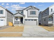 Two-story house with gray siding, attached garage, and landscaping at 17811 E 93Rd Ave, Commerce City, CO 80022