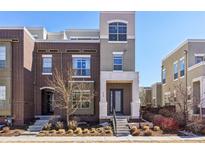 Modern two-story townhome featuring brick and stucco exterior, landscaping, and covered entry at 5438 Valentia St, Denver, CO 80238