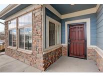 Inviting front entrance with stone accents and a charming red door at 12444 Madison Way, Thornton, CO 80241