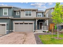 Inviting two-story home with a charming front porch, brick driveway, and attached two-car garage at 645 Flintwood Pl, Lafayette, CO 80026