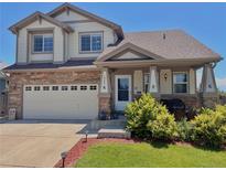 Charming two-story home featuring a stone and siding exterior, complemented by a well-manicured front yard and attached garage at 16352 E 104Th Way, Commerce City, CO 80022