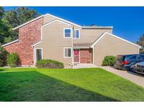 Charming townhouse featuring a well-maintained lawn, red door, and a blend of brick and siding exterior at 7476 E Arkansas Ave # 35-10, Denver, CO 80231