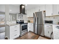 Well-lit kitchen featuring stainless steel appliances, granite countertops, and white cabinetry with dark hardwood floors at 19820 E Amherst Dr, Aurora, CO 80013