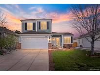 Charming two-story home with a well-manicured lawn, two car garage, and beautiful sunset backdrop at 11825 Meadowood Ln, Parker, CO 80138