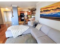 Cozy living room view into kitchen, featuring modern finishes and stylish decor with an mountain-themed painting at 601 W 11Th Ave # 318, Denver, CO 80204