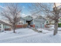 Beautiful ranch home with brick and siding exterior, nestled on a snow-covered lot at 23480 E Moraine Pl, Aurora, CO 80016