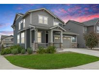 Charming two-story home featuring a covered front porch, well-manicured lawn, and a two-car garage with beautiful landscaping at 12940 Brier Ct, Firestone, CO 80504