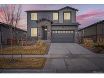 Charming two-story home boasts a stone facade and well-manicured lawn at dusk at 3847 N Catawba Way, Aurora, CO 80019