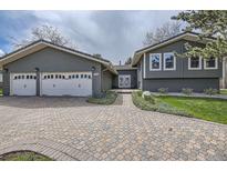 Inviting exterior features a well-maintained lawn, charming landscaping, and a brick driveway leading to the home's entrance and garage at 5254 W Oberlin Dr, Denver, CO 80235