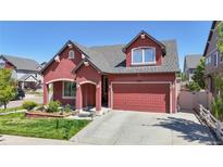 Charming red two-story home with a well-manicured lawn, beautiful landscaping, and a two-car garage at 18009 E 47Th Pl, Denver, CO 80249